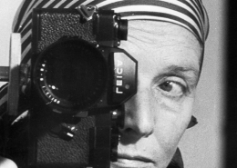 Leonore Mau, Selbstporträt im Spiegel mit Leica und gestreiftem Kopftuch, Hamburg 1980